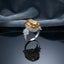 Silver Imperial Citrine Oval CZ Pavé Halo Flower Shoulder Cocktail Ring — dramatic angled side view: rhodium-plated ring with massive golden honey citrine oval center, full CZ micro-pavé halo, twin 5-petal CZ flower shoulders, and pavé band, on dark mirror surface with grey silk fabric backdrop