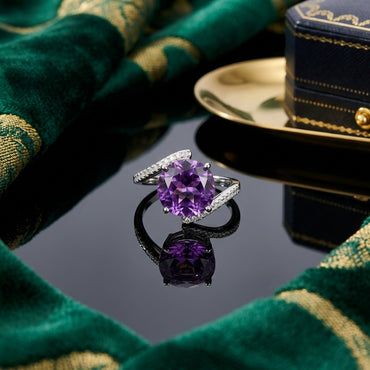 Silver-Tone Large Round Amethyst Purple CZ Solitaire Bypass Pavé Band Statement Ring on black reflective surface with emerald green gold-embroidered fabric and navy blue gold jewelry box backdrop