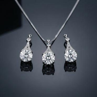 Silver-Tone Large Round Brilliant CZ Solitaire & Pavé Teardrop Cap Pendant Necklace & Drop Earrings Jewelry Set flat lay on dark reflective surface showing pendant and matching drop earrings