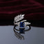 Silver Marquise Leaf Crown Princess CZ Adjustable Cocktail Ring in Sapphire Blue — rhodium-plated open adjustable ring with marquise white CZ leaf crown, micro-pavé arc, and deep royal sapphire blue princess cut center stone, on dark mirror with burgundy velvet backdrop