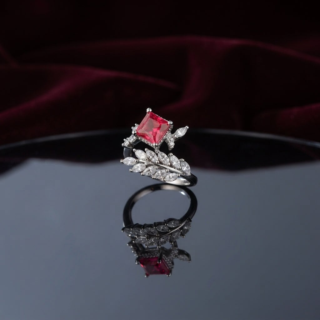 Silver Marquise Leaf Crown Princess CZ Adjustable Cocktail Ring in Ruby Red — rhodium-plated open adjustable ring with marquise white CZ leaf crown, micro-pavé arc, and deep ruby crimson red princess cut center stone, on dark mirror with burgundy velvet backdrop
