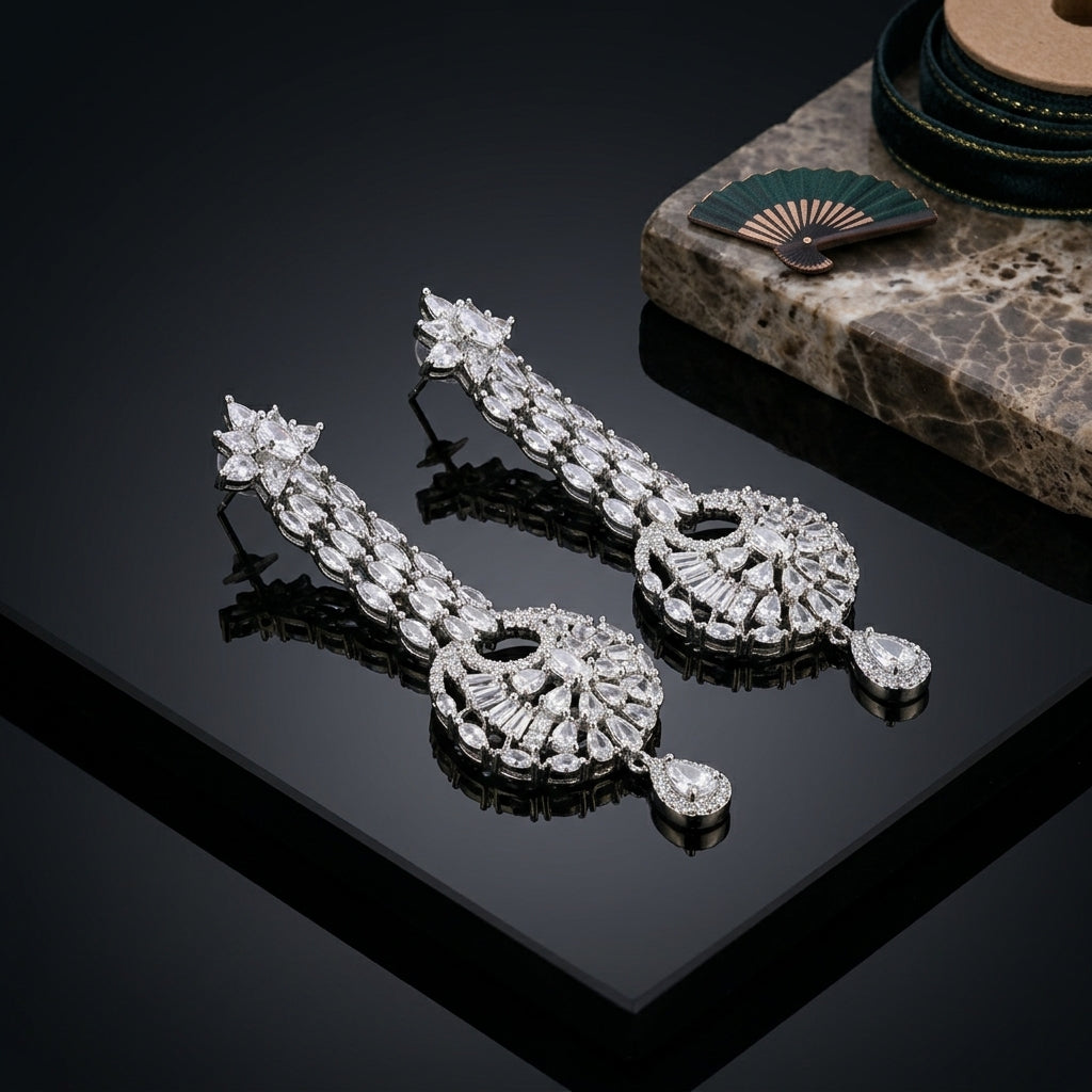Silver-Tone Marquise Pear CZ Cluster Top Double Baguette Waterfall Column & Baguette Sunburst Fan Medallion Pear Drop Chandelier Earrings on black mirror surface with marble stone prop and teal green silk fan backdrop