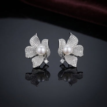 Silver-Tone Micro-Pavé CZ Orchid Flower Pearl Center Statement Stud Earrings on dark mirror surface with deep burgundy velvet backdrop