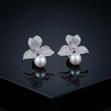 Silver-Tone Micro-Pavé CZ Triple Leaf Flower Cap & South Sea Pearl Stud Earrings on black mirror surface with dark background