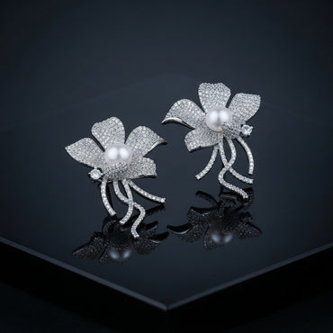 Silver-Tone Micro-Pavé CZ Wild Orchid Pearl Center & Pavé Tendril Stem Statement Earrings on black mirror surface with dark background