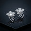 Silver-Tone Micro-Pavé CZ Wild Orchid Pearl Center & Pavé Tendril Stem Statement Earrings on black mirror surface with dark background