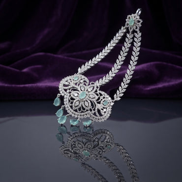 Silver Mint Green CZ Floral Filigree and Marquise Wheat Chain Grand Maang Tikka on dark mirror surface with purple velvet backdrop showing rhodium silver double-strand marquise white CZ wheat chain with 3-medallion open filigree flower pendant mint green CZ cabochon centres and 5 mint green pear drop fringe