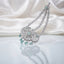Silver Mint Green CZ Floral Filigree and Marquise Wheat Chain Grand Maang Tikka on white satin backdrop showing rhodium silver double-strand marquise white CZ wheat chain with 3-medallion open filigree flower pendant mint green CZ accents and graduated mint green pear drop fringe