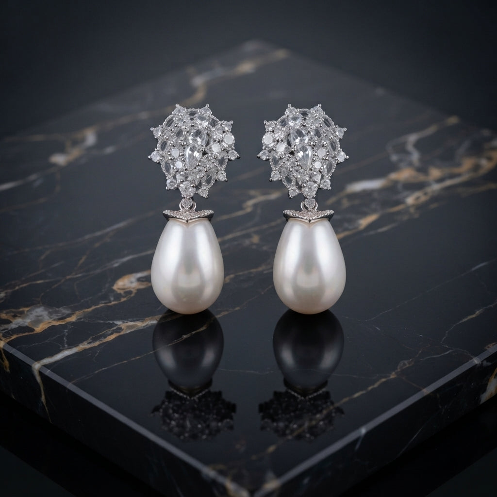 Silver-Tone Mixed-Cut CZ Dome Cluster Cap & Baroque Pearl Teardrop Drop Earrings on black marble surface with dark silk fabric backdrop