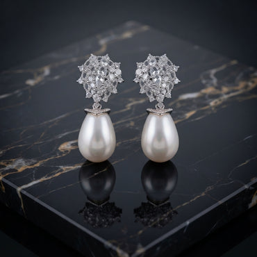 Silver-Tone Mixed-Cut CZ Dome Cluster Cap & Baroque Pearl Teardrop Drop Earrings on black marble surface with dark silk fabric backdrop