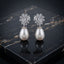 Silver-Tone Mixed-Cut CZ Dome Cluster Cap & Baroque Pearl Teardrop Drop Earrings on black marble surface with dark silk fabric backdrop
