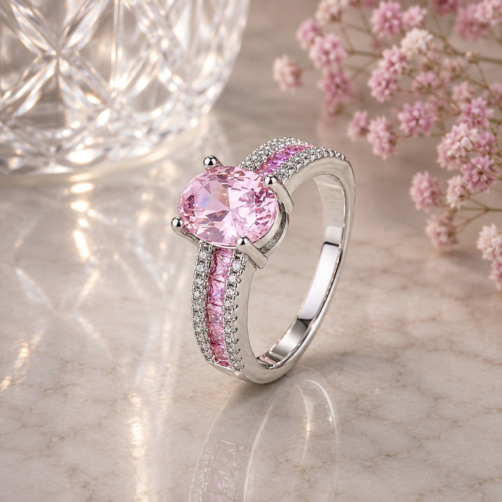 Silver-Tone Oval Pink CZ Solitaire Baguette & Pavé Double Shoulder Engagement Ring on blush marble surface with crystal bokeh light orb and pink baby’s breath flowers backdrop