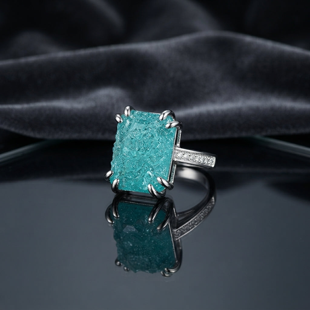 Silver Paraiba Teal Raw Crackle Emerald-Cut CZ Statement Cocktail Ring on dark grey mirror surface with charcoal velvet drape backdrop
