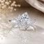 Silver-Tone Pear Cut White CZ Solitaire & Marquise Flower Open Cocktail Ring on reflective surface with pearl strands and blush silk backdrop