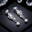 Silver-Tone Pearl & CZ Cascading Wave Long Drop Earrings product shot on dark reflective surface with crystals