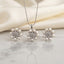 Silver Pearl CZ Daisy Flower Pendant Necklace Earrings Set on white marble surface with cream silk fabric backdrop showing rhodium silver-tone snake chain pendant necklace and matching pair of stud earrings each featuring snowflake daisy flower cluster with marquise-cut white CZ star petal arrangement and outer ring of round faux pearl cabochons with mirror reflection below