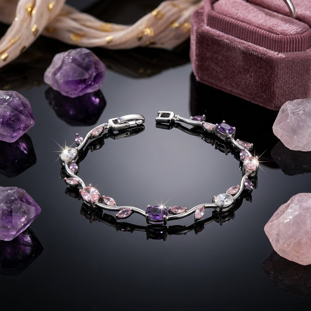 Gold-Tone White CZ Oval & Marquise Vine Wave Tennis Bracelet on dark reflective surface with gold jewelry box and crystal perfume bottle backdrop