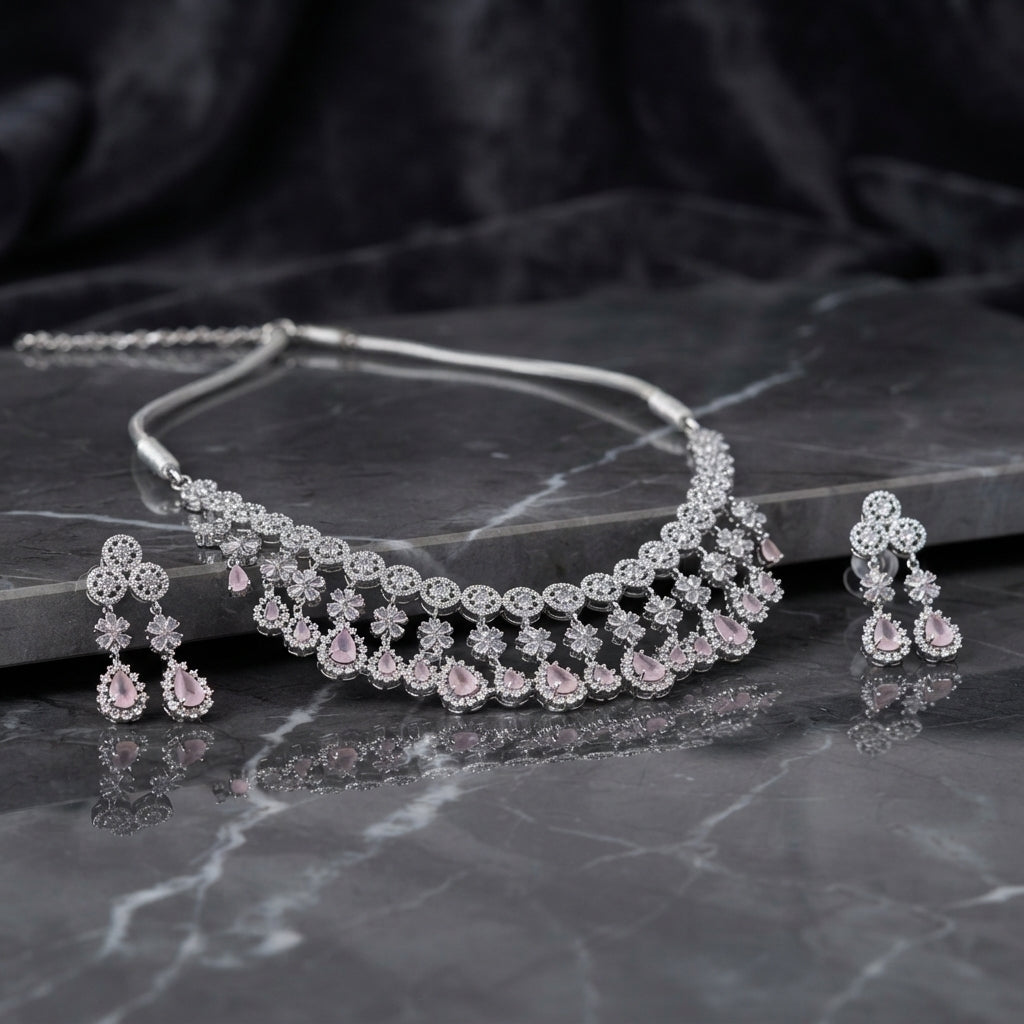 Silver Rose Pink CZ Floral Fringe Collar Necklace and Chandelier Earrings Bridal Set — rhodium silver-tone 2-piece bridal set with continuous round CZ halo station collar necklace with 5-petal CZ flower connectors and rose pink pear CZ fringe drops and matching 3-drop chandelier earrings with round CZ halo stud and rose pink pear CZ drops displayed on grey marble surface with dark satin backdrop