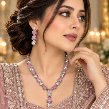 Silver Rose Pink Enamel and Round Polki CZ Necklace and Earrings Set worn by Pakistani female model in dusty rose lehenga in chandelier backdrop setting showing graduated V-drop necklace with alternating rose pink enamel trapezoid links and brilliant round polki moissanite-illusion CZ with white CZ micro-pavé borders and matching 3-tier drop earrings