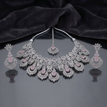 Silver Rose Quartz CZ Grand Mughal Bib Necklace Maang Tikka and Cascade Drop Earrings Bridal Set — rhodium silver-tone 3-piece grand bridal set with 5-unit Mughal arch bib necklace featuring oval rose quartz CZ cabochons white CZ micro-pavé scrollwork and radiating marquise CZ leaf crown borders matching maang tikka with rose quartz CZ floral crown and 4-tier cascade drop earrings displayed on dark grey mirror surface with black satin backdrop