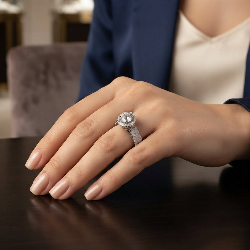 Silver Round CZ Solitaire Double Halo Triple Pave Split Shank Engagement Ring standing upright on dark mirror surface with dark charcoal satin backdrop showing large round brilliant clear CZ solitaire in 4-claw setting with double round white CZ halo inner and outer and wide triple-row micro-pave split shank band in rhodium silver with mirror reflection below