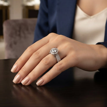 Silver Round CZ Solitaire Double Halo Triple Pave Split Shank Engagement Ring standing upright on dark mirror surface with dark charcoal satin backdrop showing large round brilliant clear CZ solitaire in 4-claw setting with double round white CZ halo inner and outer and wide triple-row micro-pave split shank band in rhodium silver with mirror reflection below