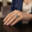 Silver Round CZ Solitaire Double Halo Triple Pave Split Shank Engagement Ring standing upright on dark mirror surface with dark charcoal satin backdrop showing large round brilliant clear CZ solitaire in 4-claw setting with double round white CZ halo inner and outer and wide triple-row micro-pave split shank band in rhodium silver with mirror reflection below