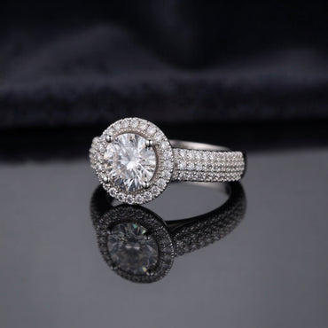 Silver Round CZ Solitaire Double Halo Triple Pave Split Shank Engagement Ring worn on ring finger of female model in navy blue blazer and white top in luxury jewelry boutique backdrop showing large round brilliant clear CZ solitaire with double round white CZ halo and triple-row micro-pave split shank band in rhodium silver