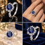 Silver Round CZ Sunflower Halo Milgrain Infinity Shoulder Cocktail Ring in Amethyst Purple variant 4-scene composite showing dark mirror flat lay top left hand worn top right marble surface bottom left and navy velvet box bottom right with large amethyst purple round brilliant CZ solitaire sunflower halo and infinity milgrain shoulders in rhodium silver