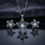 Silver Sapphire Blue CZ Baguette Flower Pendant Necklace and Stud Earrings Set on dark mirror surface with charcoal backdrop showing rhodium silver 5-petal flower pendant with 10 sapphire blue baguette CZ in V-fan petals on slim box chain flanked by matching flower stud earrings