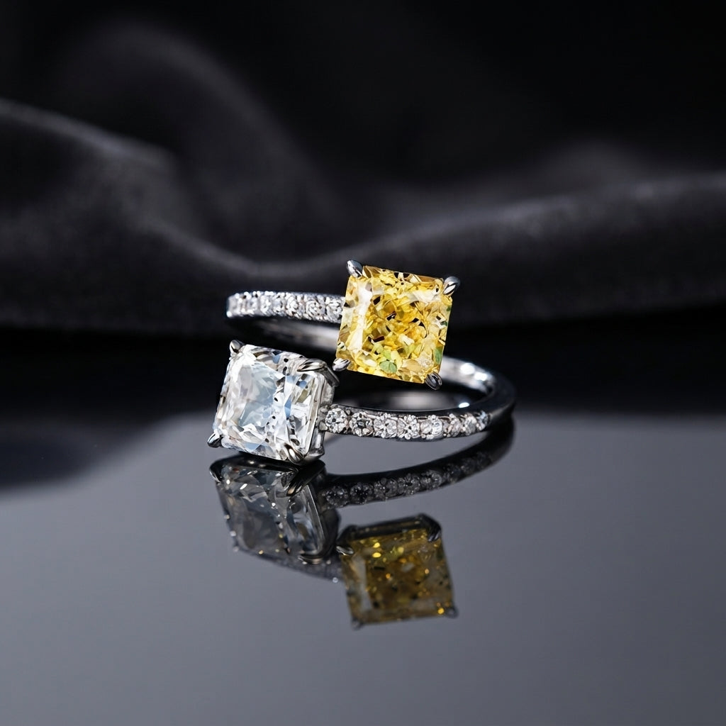 Silver Toi et Moi Dual Cushion CZ Bypass Ring in White and Yellow CZ variant flat lay on grey mirror surface with dark charcoal satin backdrop showing open bypass ring with full white CZ micro-pave shank and two large cushion cut CZ solitaires one clear white and one vivid yellow canary with mirror reflection
