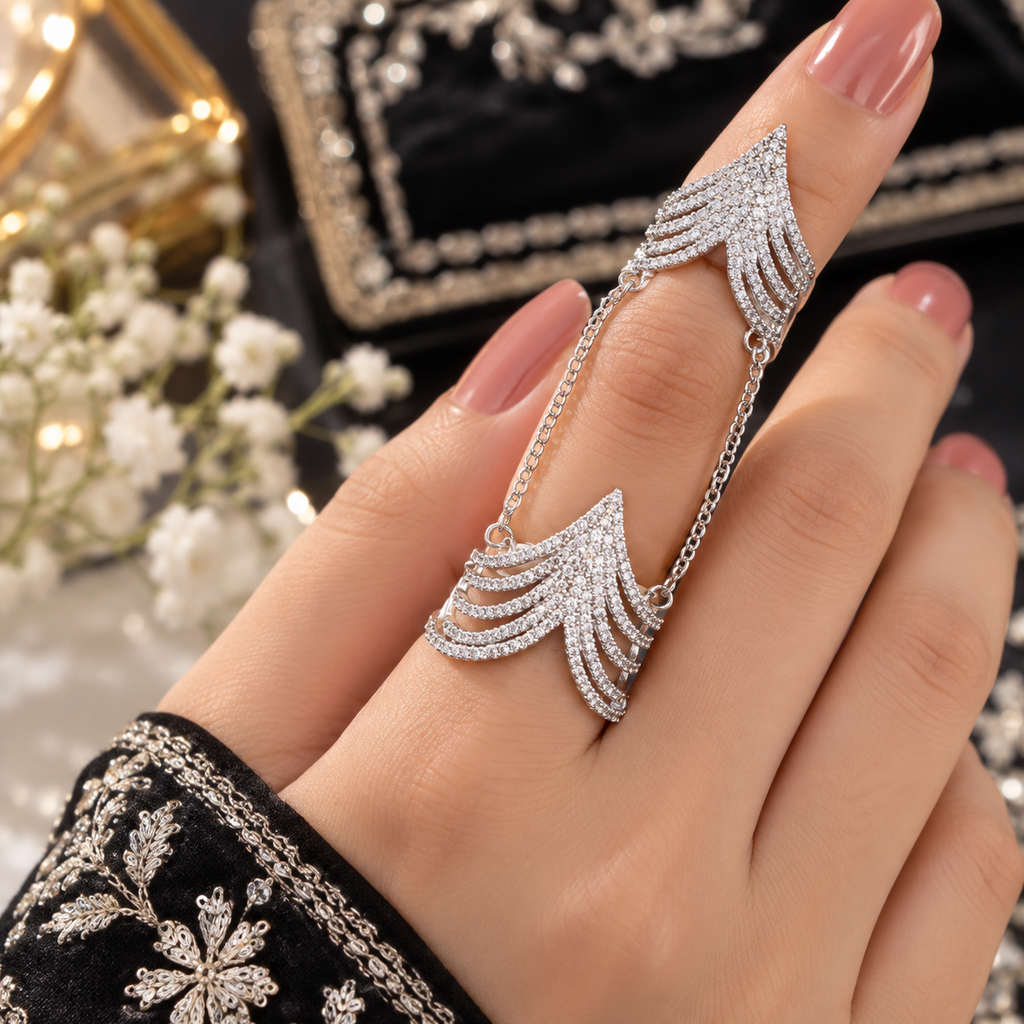 Silver-tone chain-linked double ring worn on one finger, showing two layered chevron sections with clear accents.