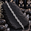 Silver-tone bracelet with repeating intertwined open loops, rows of clear rectangular accents and small round-accent connecting details.