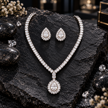 Silver-tone rectangular-accent necklace with a clear teardrop pendant and radiating halo, alongside matching clear teardrop earrings.