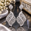 Silver-tone openwork drop earrings with leaf-like tops, tapered rectangular clear accents and sweeping S-shaped clear-accent bands.