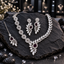 Silver-tone asymmetric necklace with open teardrop links, clear-looking leaf details and a deep plum teardrop centre, with matching earrings and bindia.