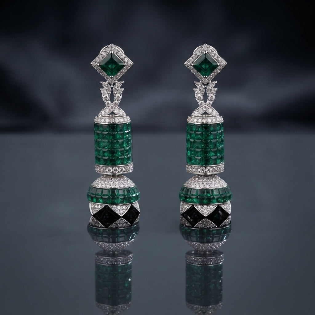 Silver-Tone Emerald Green CZ Cylinder and Ball Jhumka Drop Earrings with Black Enamel and White CZ Pave displayed upright on dark grey mirror surface with dark silk drape backdrop showing pair of long drop jhumka earrings with square emerald-green CZ sugarloaf stud top white CZ pave halo X bow-knot connector cylindrical invisible-set emerald CZ drum with dome cap and large round ball with emerald CZ top half and black enamel diamond panels white CZ pave bottom half with mirror reflection below
