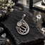 Silver-tone teardrop locket with clear accents, a floral cluster, openwork leaf motifs, curved inner loops and a decorated top bail.