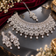 Silver-tone geometric bridal necklace set with matching earrings and maang tikka, clear faceted details, and dangling teardrop accents.
