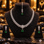 Silver-tone clear leaf necklace with a floral centre and green teardrop drop, matching floral green drop earrings and maang tikka on dark stands.