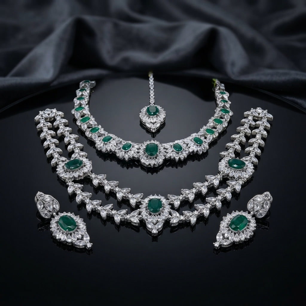 Silver-tone set with two necklaces, matching earrings, and maang tikka, featuring green and clear faceted accents.