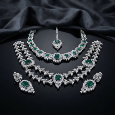 Silver-tone set with two necklaces, matching earrings, and maang tikka, featuring green and clear faceted accents.