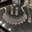 Silver-tone green American Diamond necklace, long earrings and chain-style bindia laid flat, with clear openwork panels, floral tips and white pearl-look side strands.