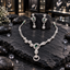 Silver-tone AD necklace with a green oval centre, asymmetric rounded clusters and an open circular pendant, alongside matching green oval drop earrings.