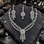 Silver-tone double-row open-link necklace with green oval accents and a floral three-drop centre, matching long earrings and floral bindia.