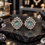 Silver-tone AD stud earrings with oval teal centres, small clear-accent halos and floral-inspired leaf borders.