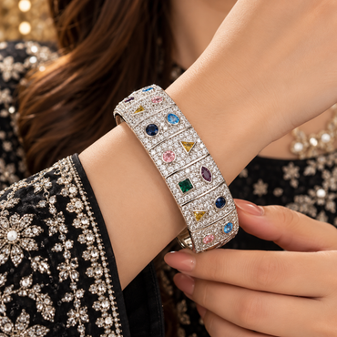 Silver-tone wide bangle worn on a wrist, with segmented clear-accent panels and multicolor geometric details.