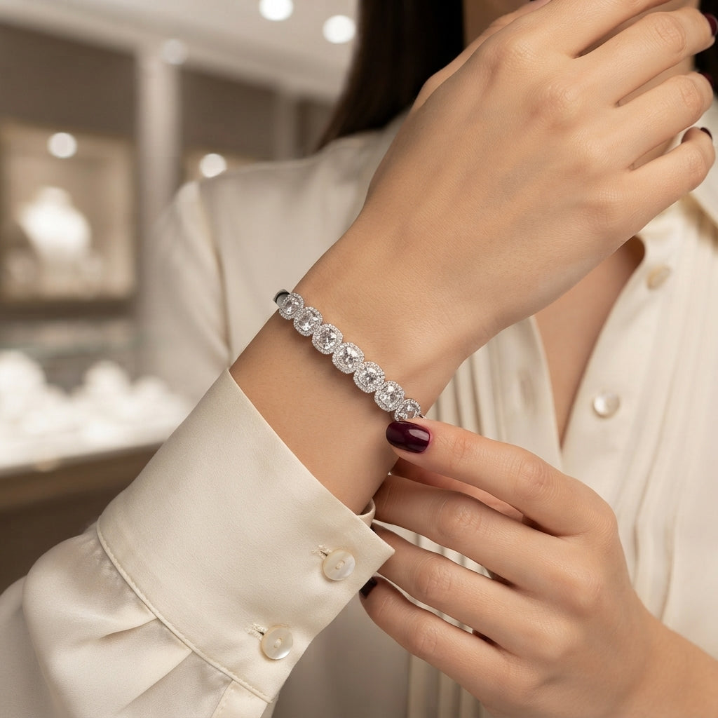 Silver-tone bangle with a row of round clear-looking halo-accent motifs, shown on a wrist.