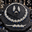 Silver-tone floral jewellery set with a navy blue-drop necklace, matching long earrings, a three-flower blue-drop bracelet and a clear-accent cluster ring.