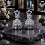 Pair of silver-tone openwork jhumka earrings with navy blue floral centres, clear sparkling domes and dangling blue and clear geometric details.